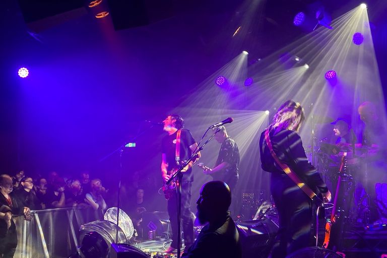 Australian alt-rock band The Drones performing live under vivid purple stage lights at The Gov venue in Adelaide.